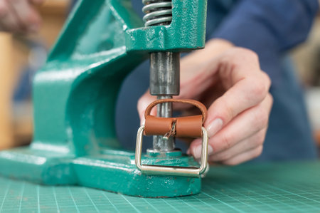 A woman attaches accessories to a leather belt. Leatherworker's workshopの写真素材