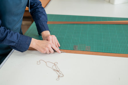 Leatherworker measuring and cutting leather in workshopの写真素材