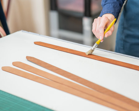 A craftsman uses a brush to cover leather partsの写真素材