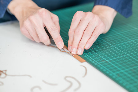 Leatherworker measuring and cutting leather in workshop
