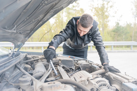 A man changes spark plugs in his carの写真素材
