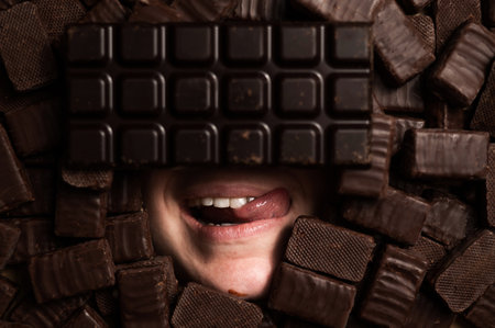 The face of a woman surrounded by chocolates. girl showing tongueの写真素材