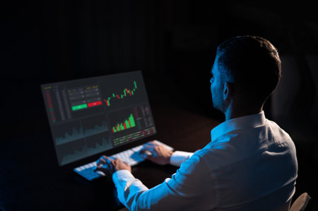 Caucasian man sits in the dark in front of a virtual screen. Stock exchange charts