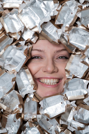 The face of a Caucasian woman surrounded by candy wrappersの写真素材