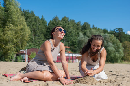 Two Caucasian women relax on the beach and build sand castlesの写真素材