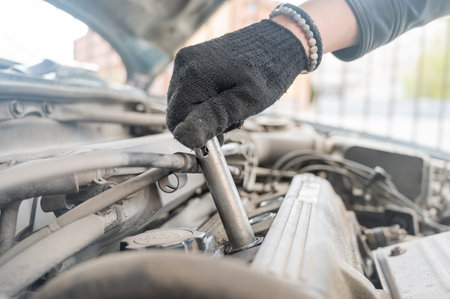 A man changes spark plugs in his car