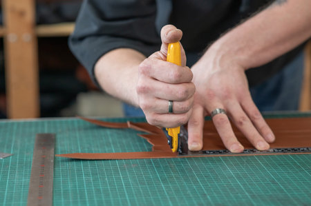 Leatherworker measuring and cutting leather in workshop