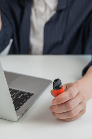 Faceless businesswoman smokes disposable vape and works on laptopの写真素材