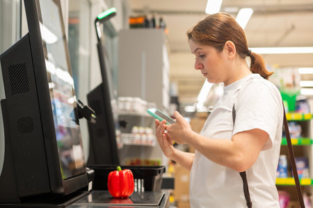 A woman buys bell peppers at a self-checkoutの写真素材
