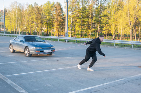 Caucasian man pulling a car with a ropeの写真素材