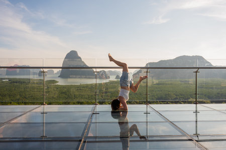 Caucasian woman doing forearm stand on glass bridge among mountains