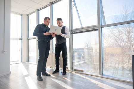 Two Caucasian men looking at a laptop and discussing workの写真素材