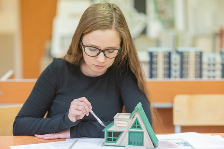 Caucasian young woman making a model of a building. Student of the construction universityの写真素材