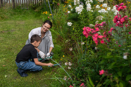 Caucasian woman and her son watering flowers in the garden