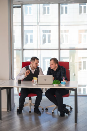 Two Caucasian men sitting at a table and discussing work