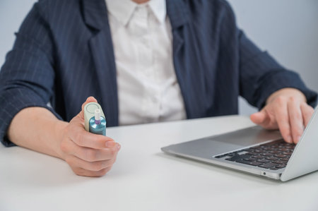 Business woman using an electronic cigarette while working on a laptop.