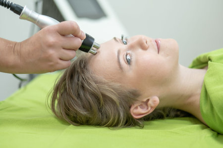 Caucasian woman undergoing radio wave RF lifting procedure in beauty salon