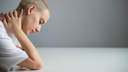 Portrait of a sad young woman sitting at a table on a white background. Copy space.