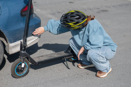 A distressed woman examines the damage after a collision between an electric scooter and a carの写真素材