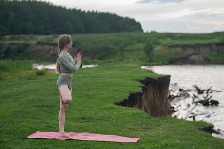 Caucasian woman doing yoga on the river bank. Tree poseの写真素材