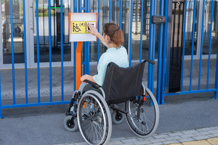 A woman in a wheelchair uses a touch-sensitive Braille help button.