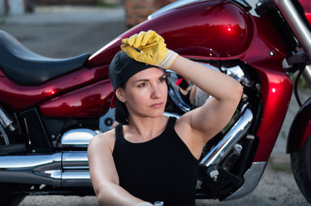 Brunette woman repairs a red motorcycleの写真素材