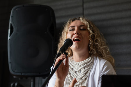Caucasian woman singing into microphone and recording herself on laptopの写真素材