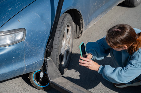 Woman examines and photographs the damage caused by a collision between an electric scooter and a carの写真素材