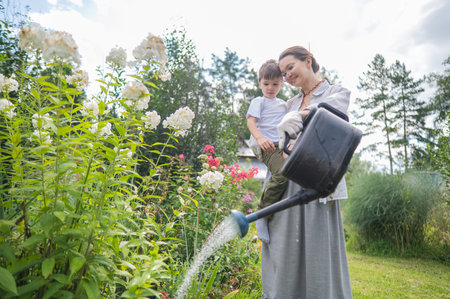 Caucasian woman and her son watering flowers in the gardenの写真素材