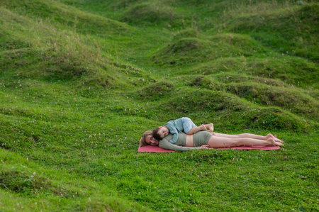 Caucasian woman doing yoga with her little son outdoorsの写真素材