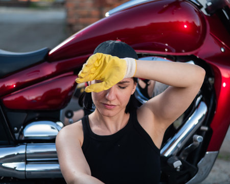 Brunette woman repairs a red motorcycleの写真素材