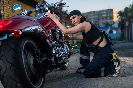 Brunette woman repairs a red motorcycleの写真素材