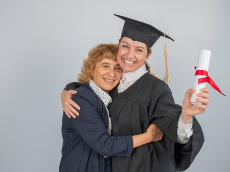 Portrait of woman in graduation gown with her motherの写真素材