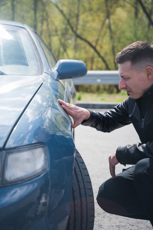 Caucasian man examines defects on his car bodyの写真素材