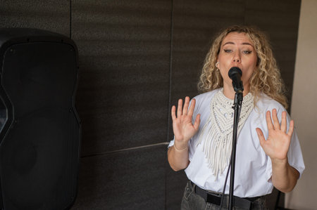 Caucasian woman singing into microphone in music studioの写真素材