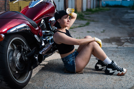 Brunette woman in denim shorts with a red motorcycle