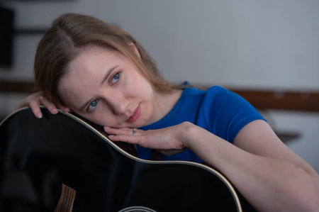 Young woman playing guitar in recording studio