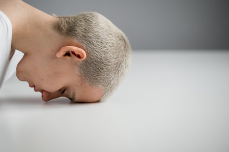 Sad woman sitting with her head on the table on a white backgroundの写真素材