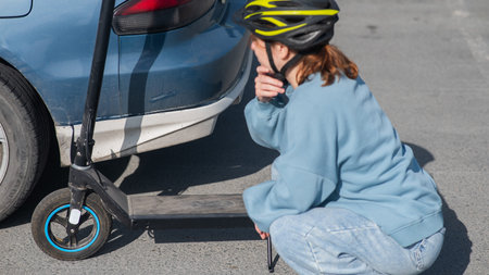 A distressed woman examines the damage after a collision between an electric scooter and a car