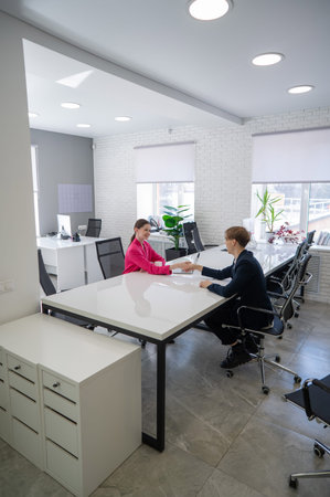 Caucasian man and woman greeting and shaking hands in office