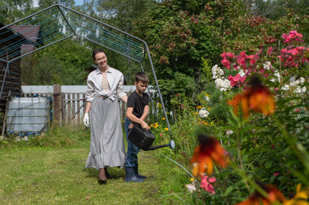 Caucasian woman and her son watering flowers in the garden