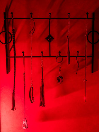 Collection of BDSM toys, whips in red lightの写真素材