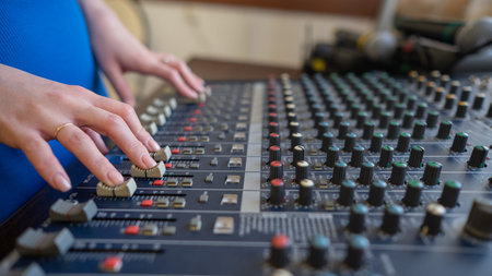 Hands Adjusting Sound Levels on Mixing Console