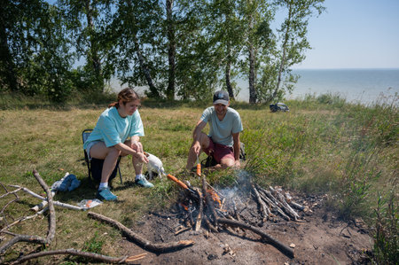 Caucasian couple roasting sausages over a fireの写真素材