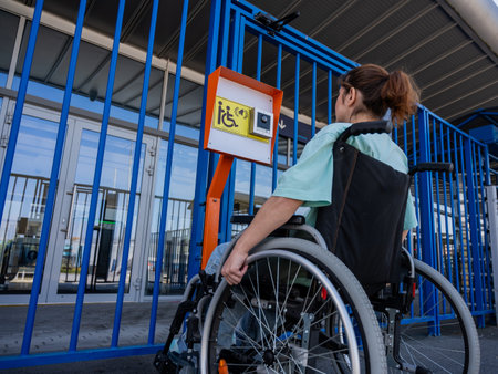 A woman in a wheelchair uses a touch-sensitive Braille help button.の写真素材
