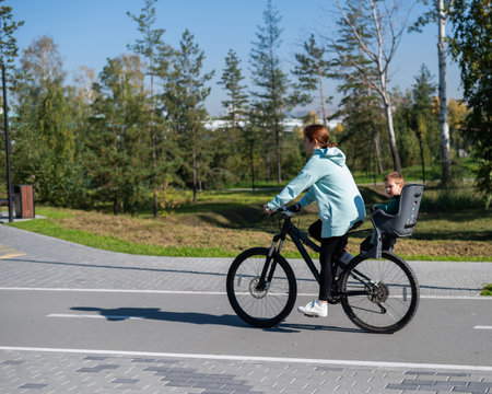 Caucasian woman rides bicycle with one-year-old son in parkの写真素材