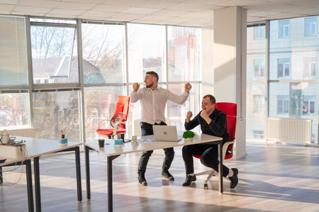 Two Caucasian men celebrate success at workの写真素材