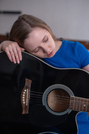 Young woman playing guitar in recording studio