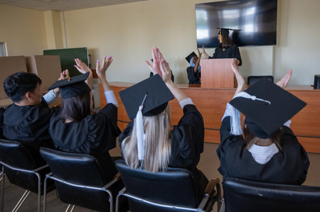 A young woman stands at the lectern and delivers a graduation speech to her classmatesの写真素材