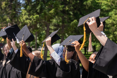 Young women of different nationalities pull graduation caps upの写真素材